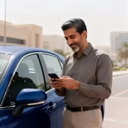 A man standing by a car using a mobile phone